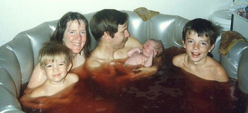 A typical water birth. No, the mother did not have triplets, they appear to be previous offspring or possible some kids the parents were babysitting for a friend. 